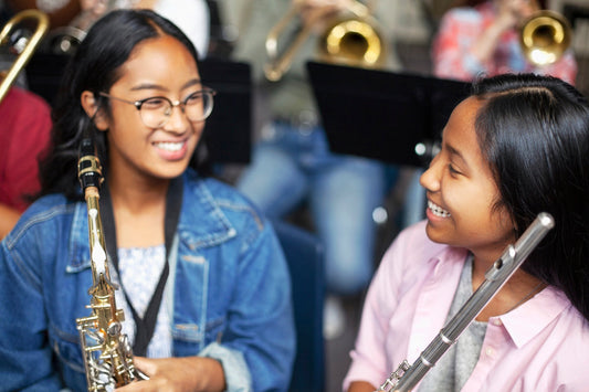 Girl with a saxophone and girl with flute laughting 