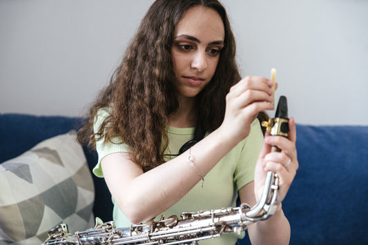 girl putting reed on saxophone
