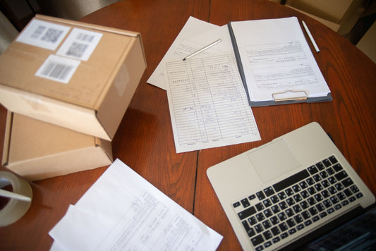 desk with a computer, papers, clipboard and boxes