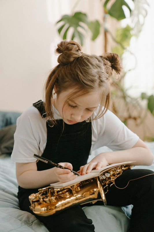 Girl writing with saxophone on her lap
