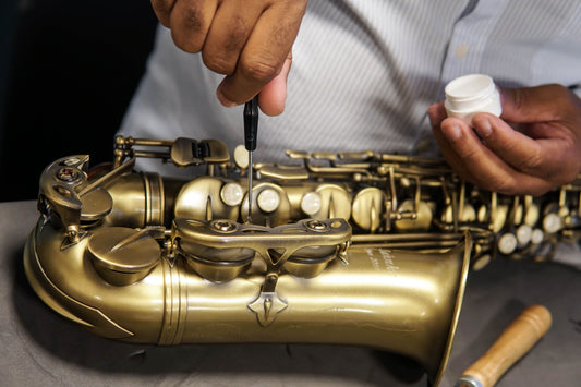 Repair technician adjusting saxophone